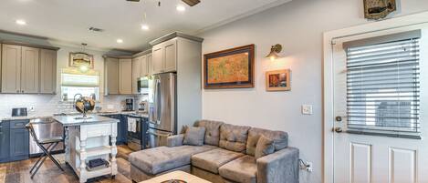 A spacious living area with a sectional sofa, a dining table, and a kitchen in the background.