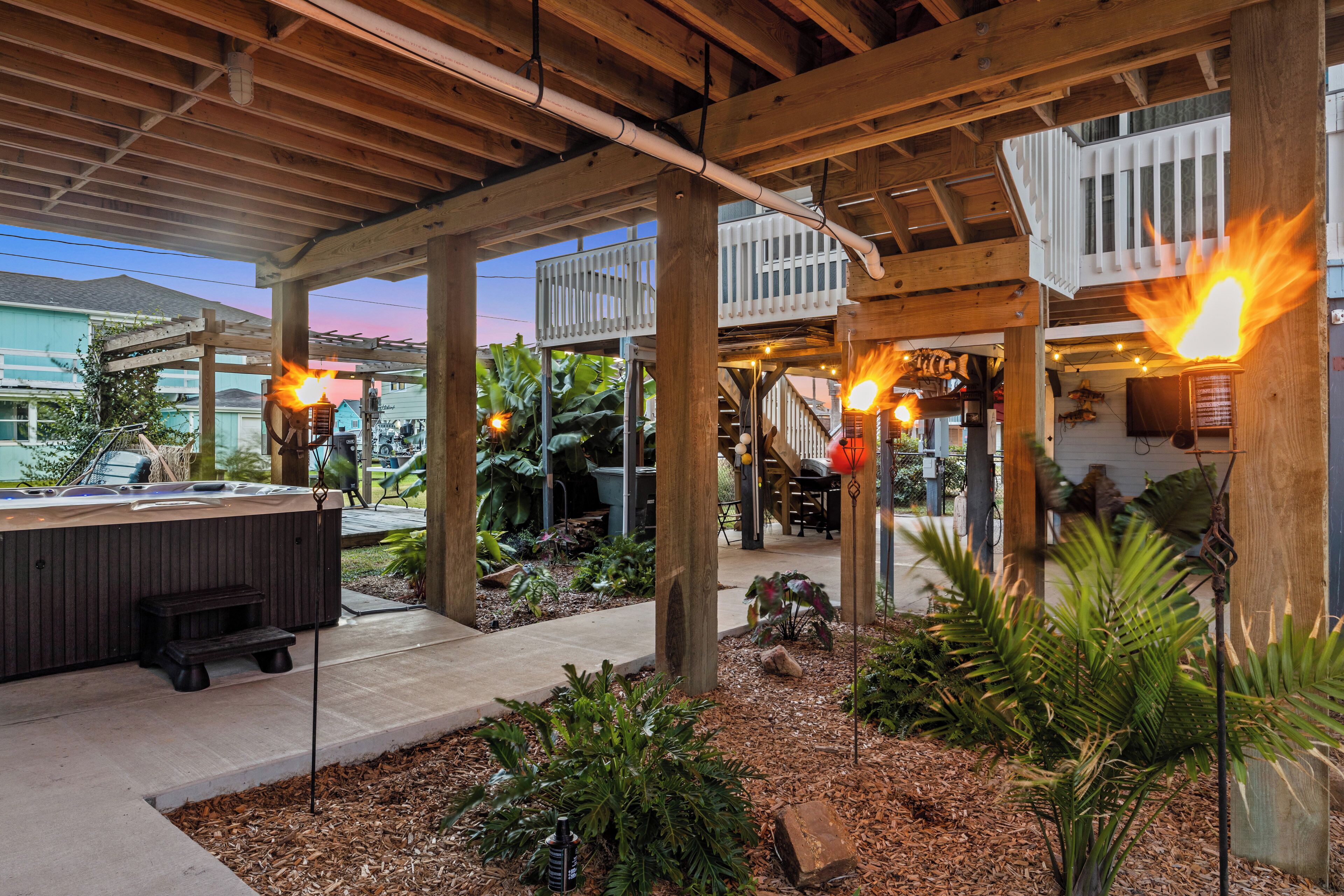 A covered outdoor area with wooden beams, a hot tub, and a fire feature.