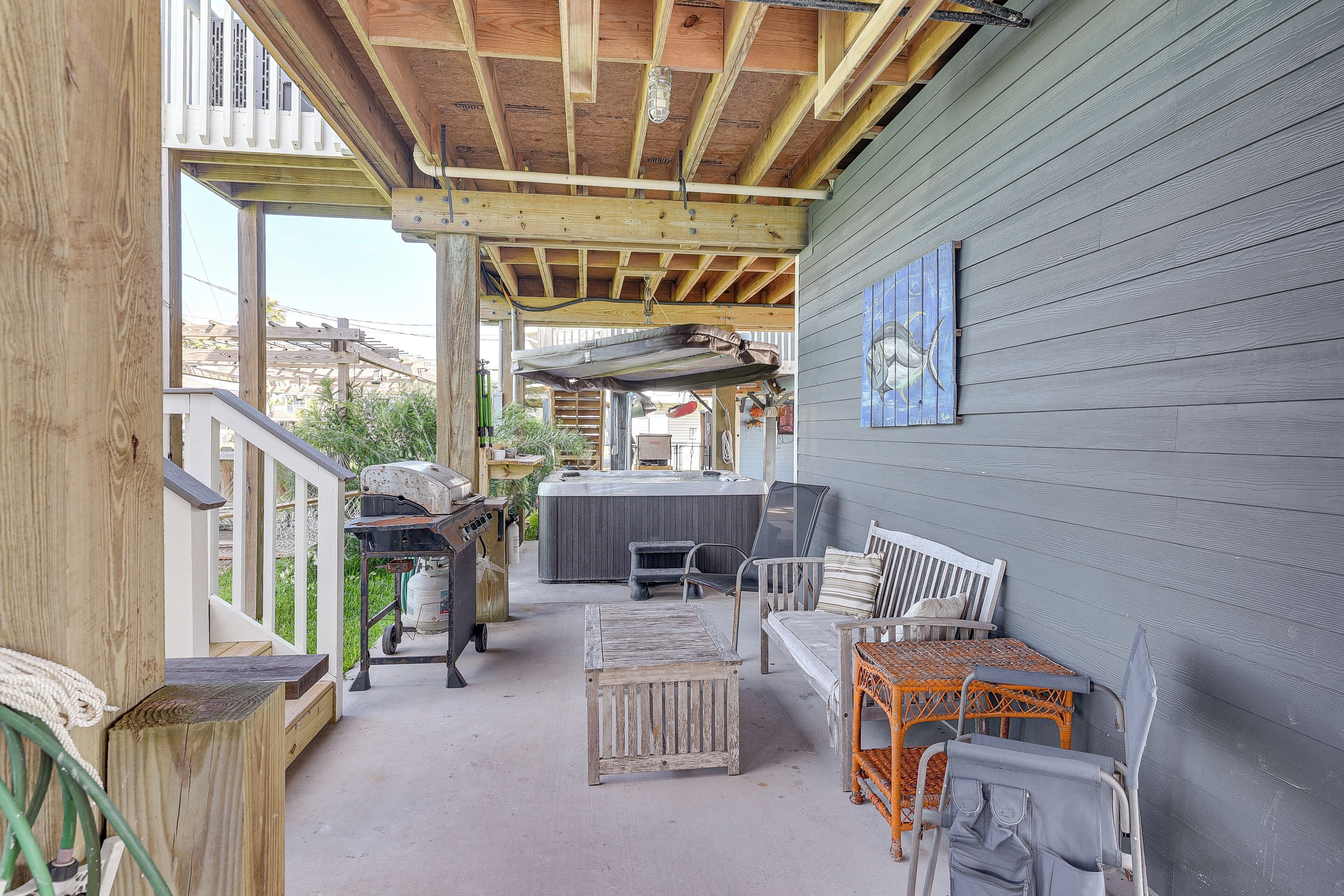 Une terrasse extérieure couverte, aménagée avec des meubles en bois, un barbecue et un jacuzzi.