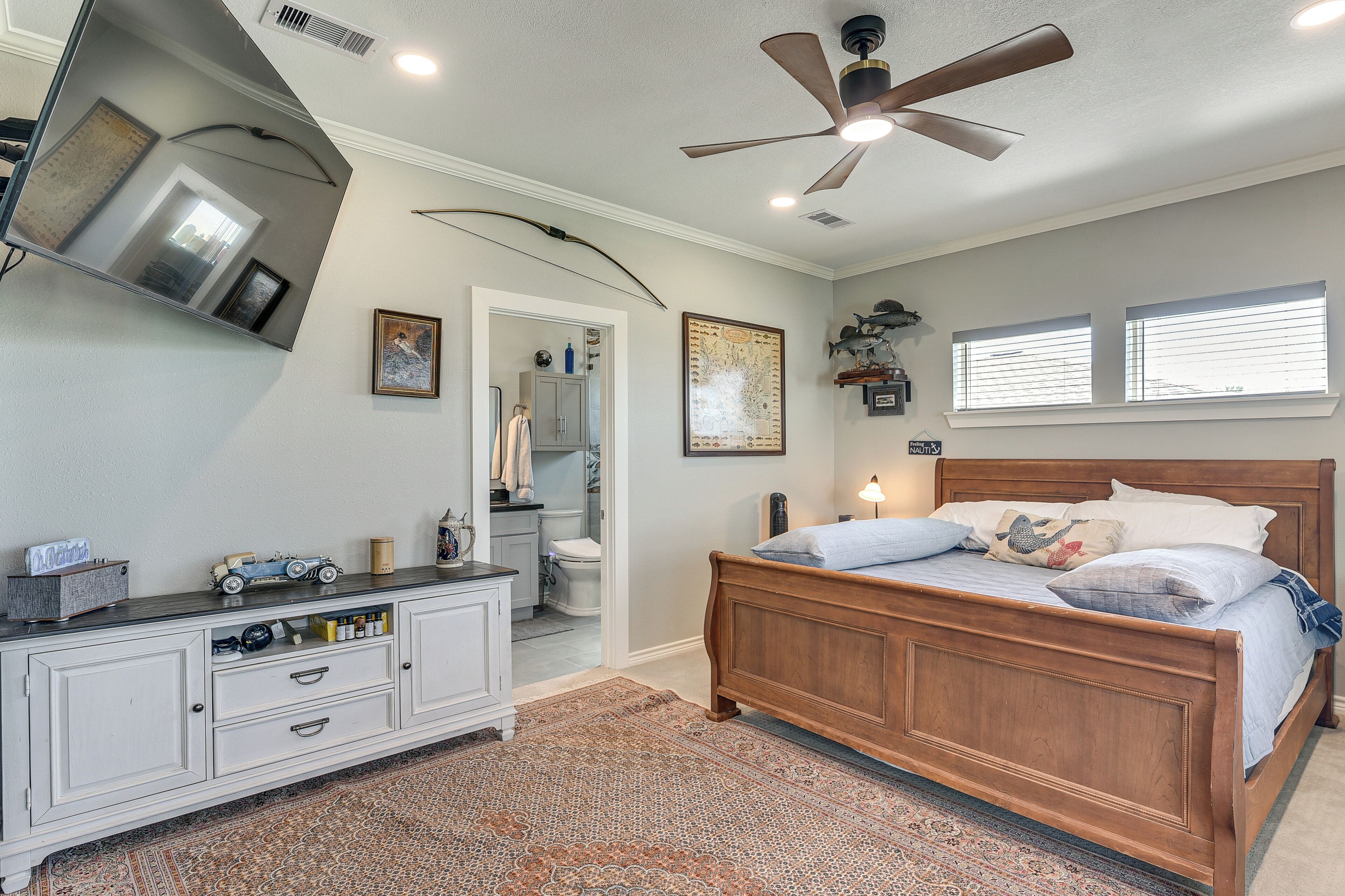 Ein Schlafzimmer mit einem hölzernen Bett, einem Deckenventilator, einem Schminktisch und einem Teppich.