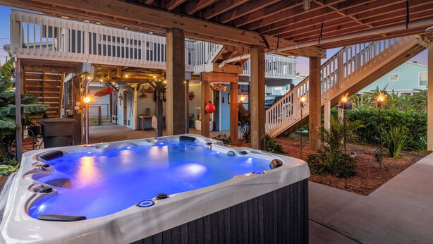 A hot tub under a wooden pergola with a view of a house and a staircase. - Walk to Sea Isle Beach: Updated Group Getaway! (Galveston)
