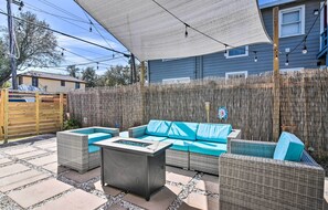 An outdoor patio with wicker furniture, a fire pit, and a bamboo fence.
