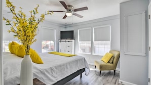 Une chambre à coucher avec un lit, une chaise, un ventilateur de plafond et une fenêtre.