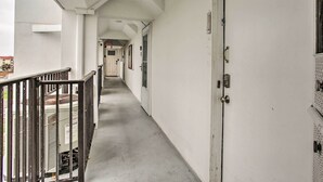 Een gang met een metalen leuning, een deur met slot en een technische kast aan de linkerkant.