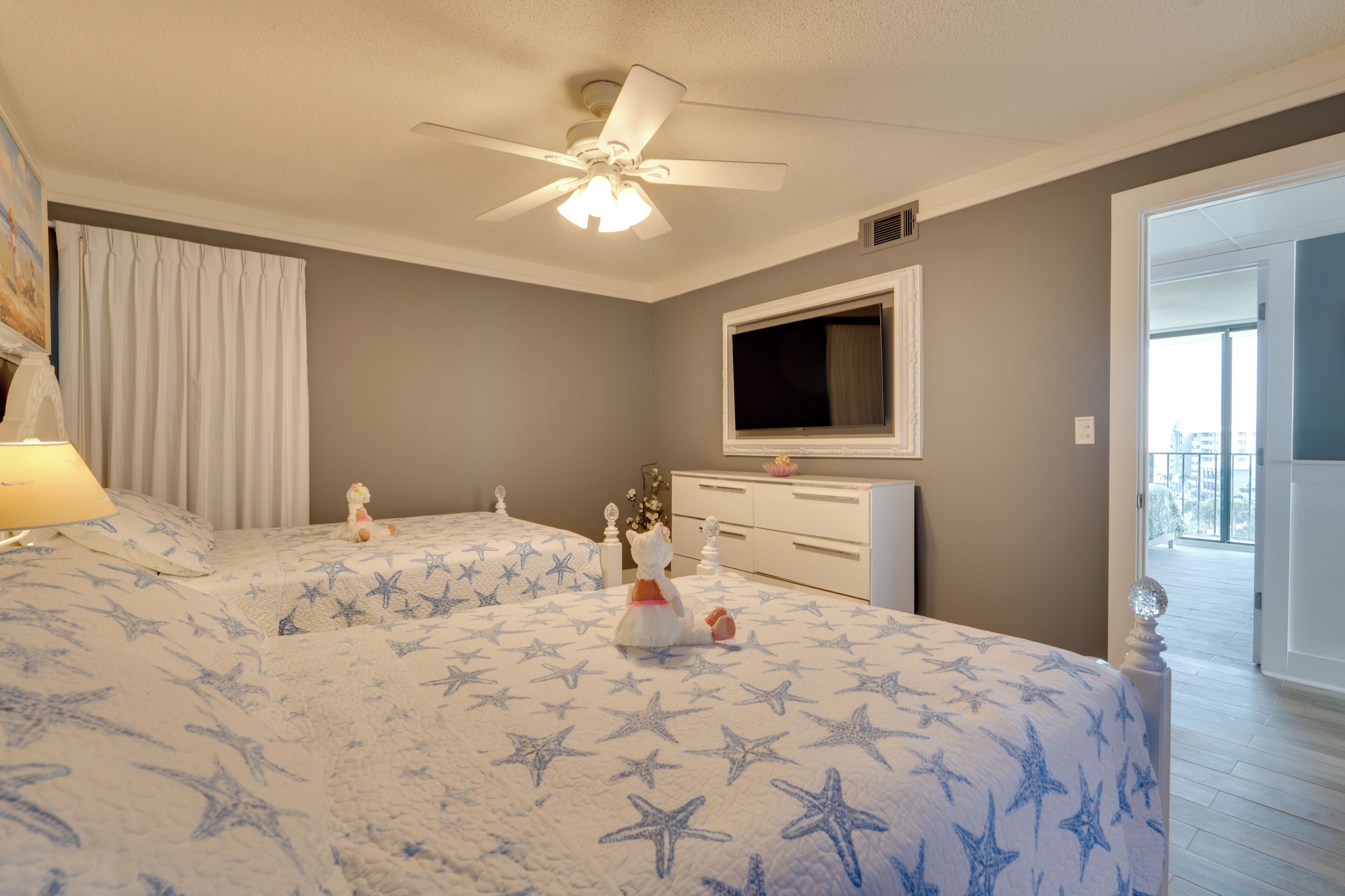 A bedroom with two beds, a ceiling fan, a TV, and a window.