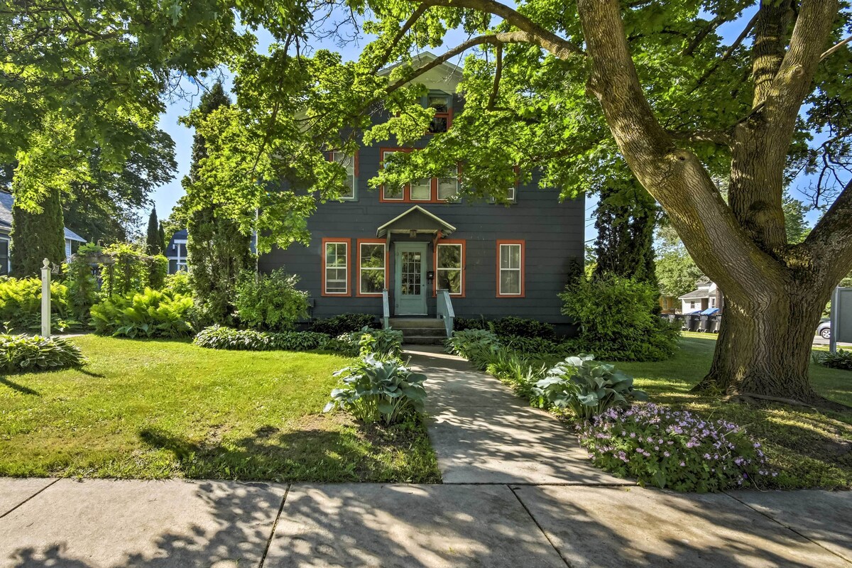 A two-story house with a front porch, surrounded by well-maintained lawns and trees.