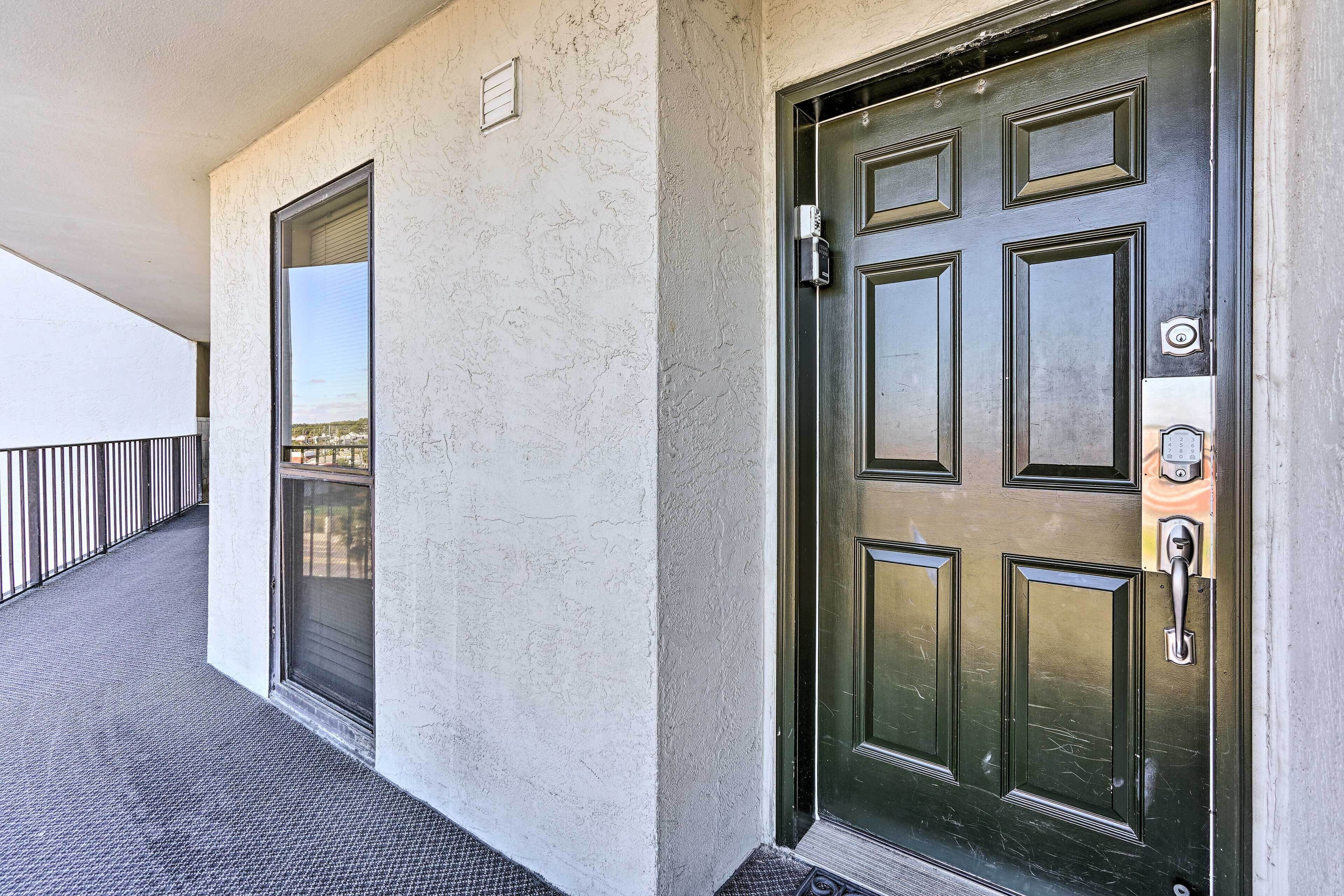 Fachada de edificio con textura, puerta verde oscuro con cerradura electrónica y ventana con reja de metal.