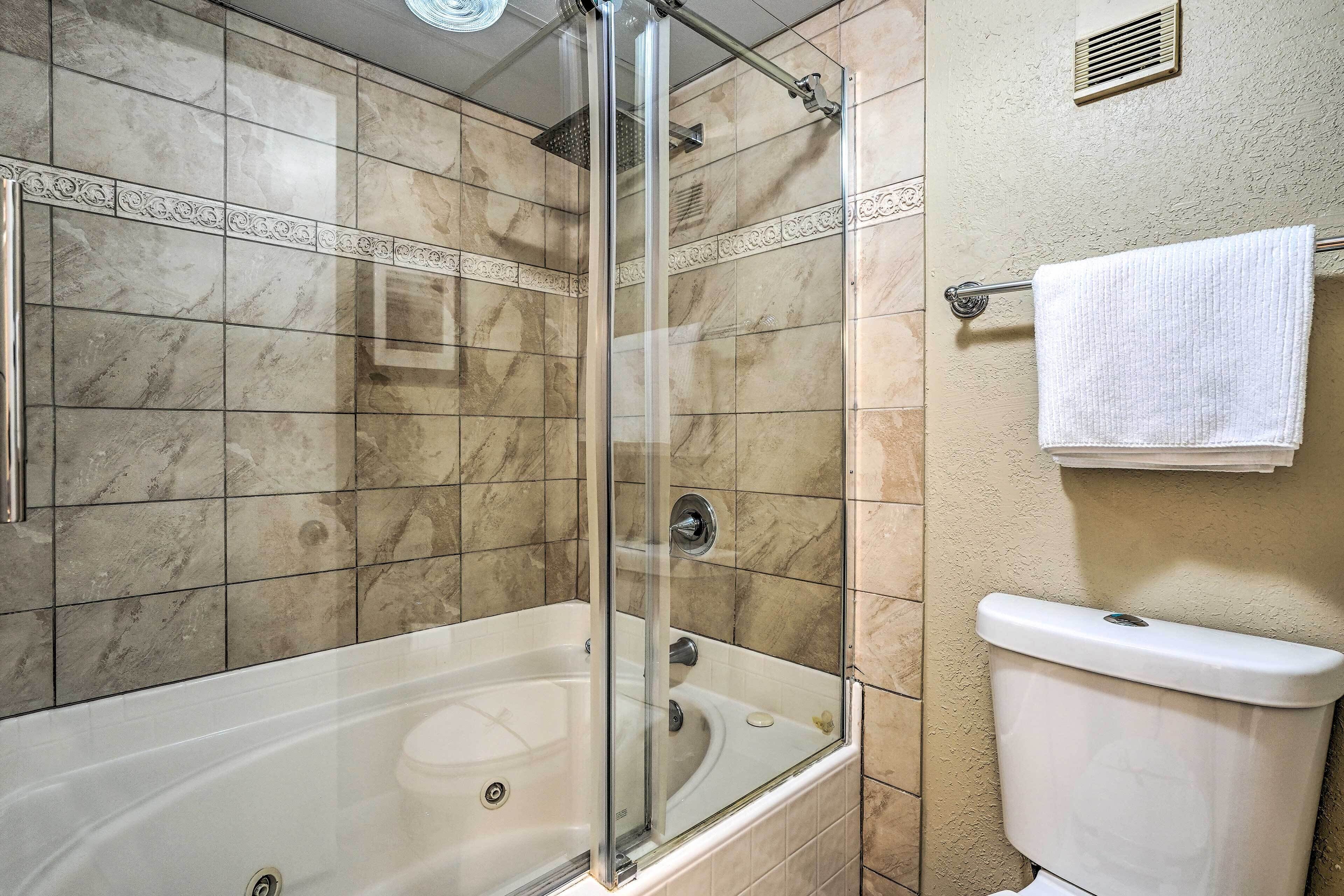 A bathroom with a glass-enclosed shower, a bathtub, and a toilet.