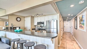 A modern kitchen with white cabinets, stainless steel appliances, and a bar area with stools. - Chic PCB Condo w/ Pool Access + Beachfront Balcony (Panama City Beach)