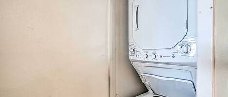 A front view of a front-loading washing machine with control panel and a dryer compartment.