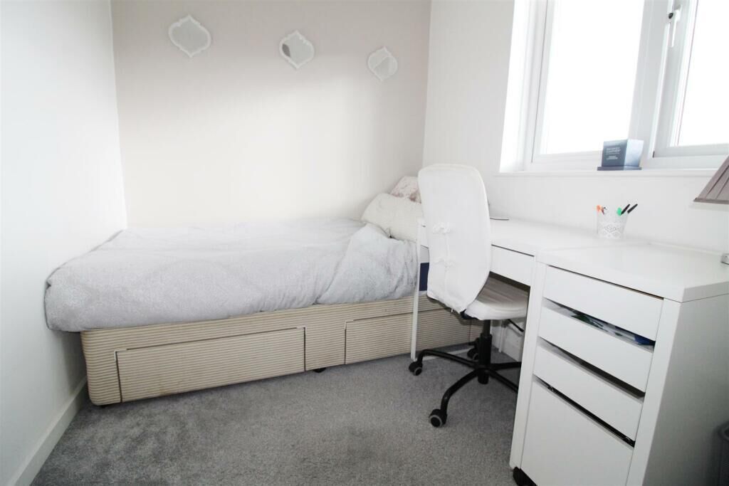 A bedroom with a bed, a desk, and a chair.