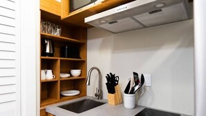 Une cuisine moderne avec des armoires en bois, un évier en acier inoxydable, une cuisinière encastrée et un four à micro-ondes placé au-dessus de la cuisinière.