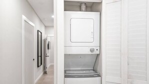 Une buanderie équipée d’un lave-linge et d’un sèche-linge à chargement frontal, d’une porte et d’un couloir menant à d’autres pièces.