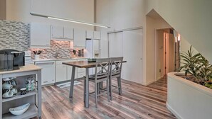 A modern kitchen with white cabinets, a wooden dining table, and a plant in the corner. - Cozy Anchorage Retreat - Near Hiking & Dtwn! (Anchorage)
