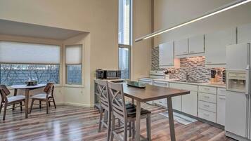 Una cocina moderna con comedor, que incluye una mesa y sillas de madera, un microondas integrado y un refrigerador.