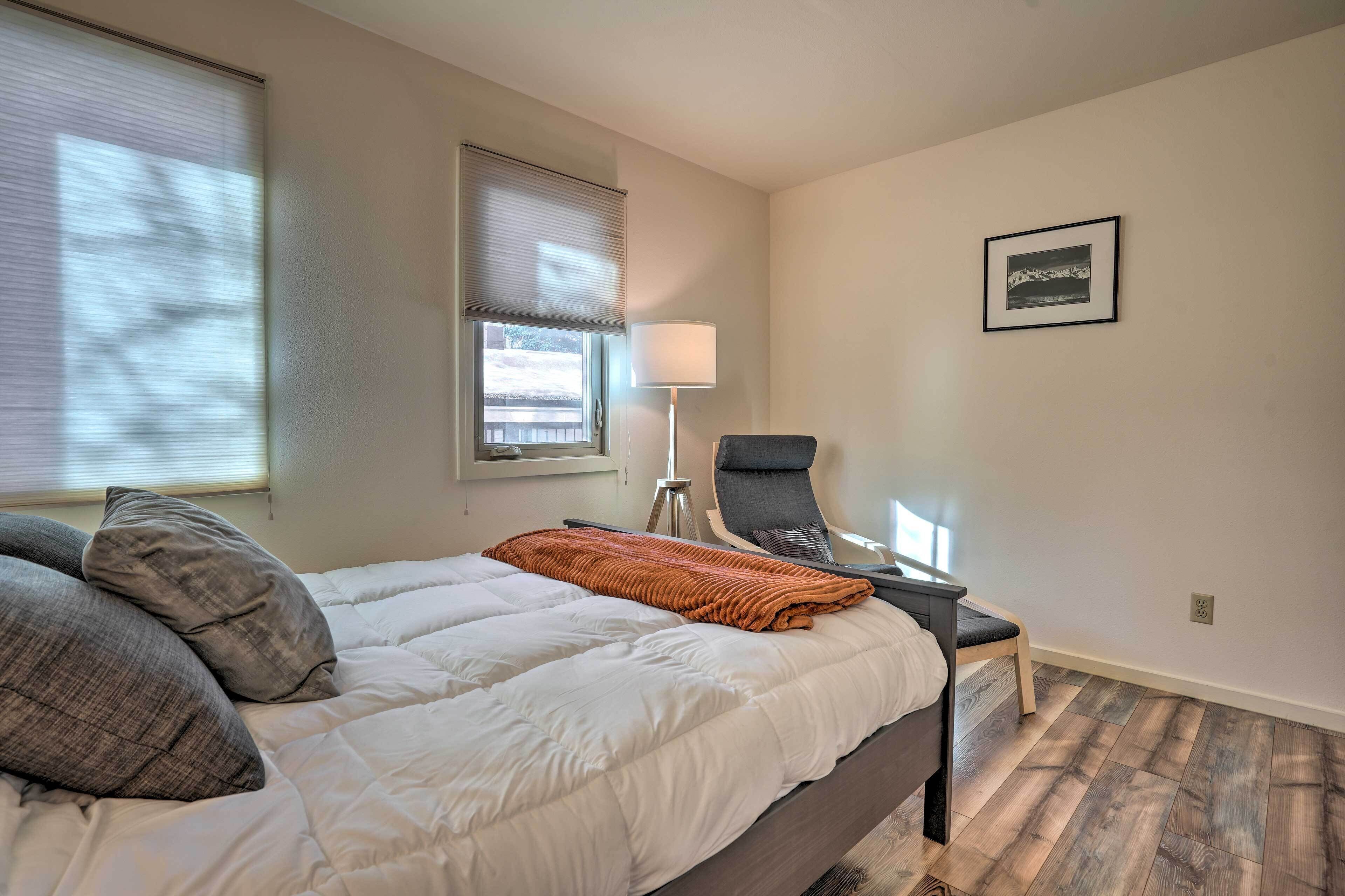 A bedroom with a bed, a chair, a lamp, and a picture on the wall.