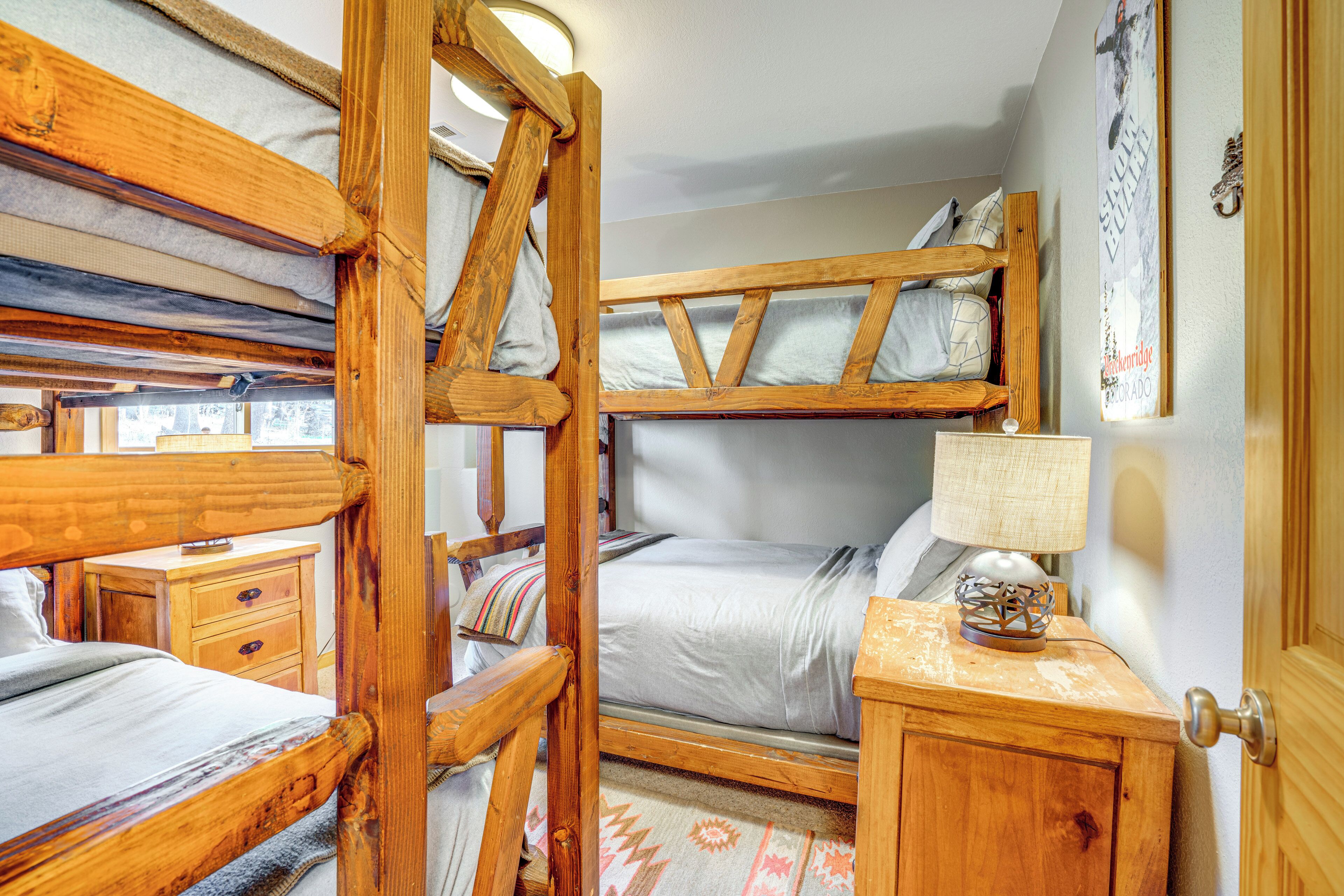 A rustic wooden room with bunk beds, a bedside table with a lamp, and a wall-mounted artwork.