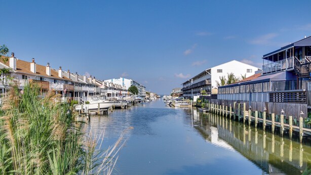 Un canal bordeado de barcos y edificios, reflejando el cielo despejado.
