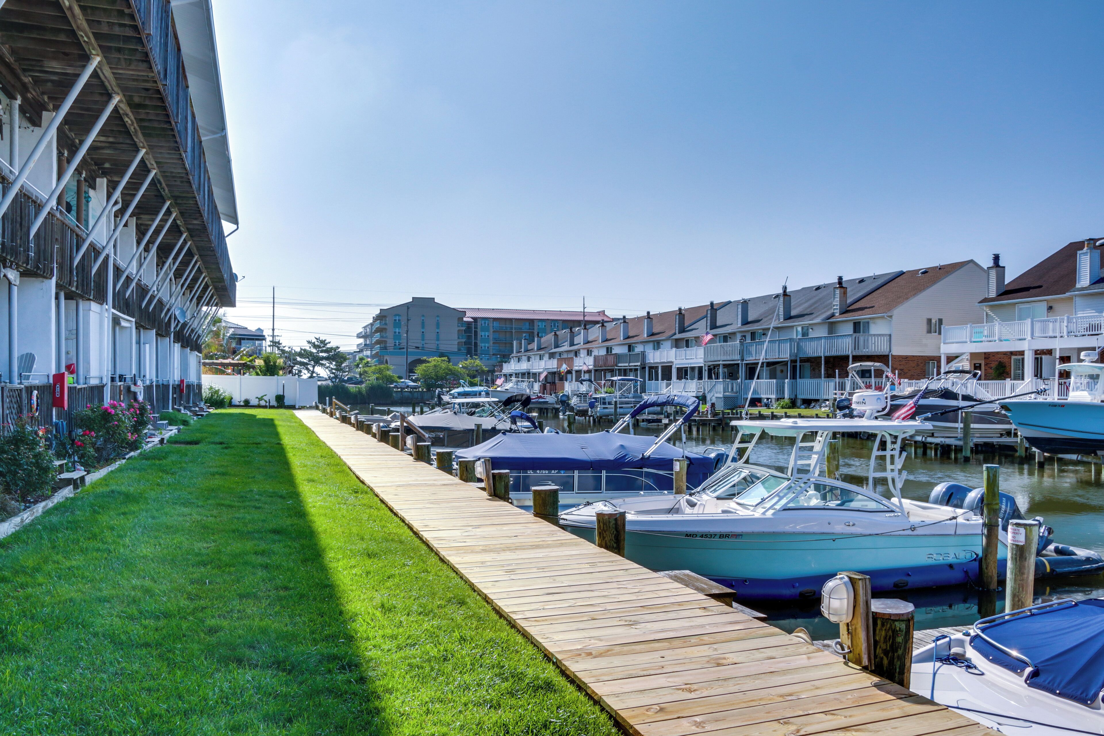 A marina with boats docked along a wooden walkway, surrounded by residential buildings.