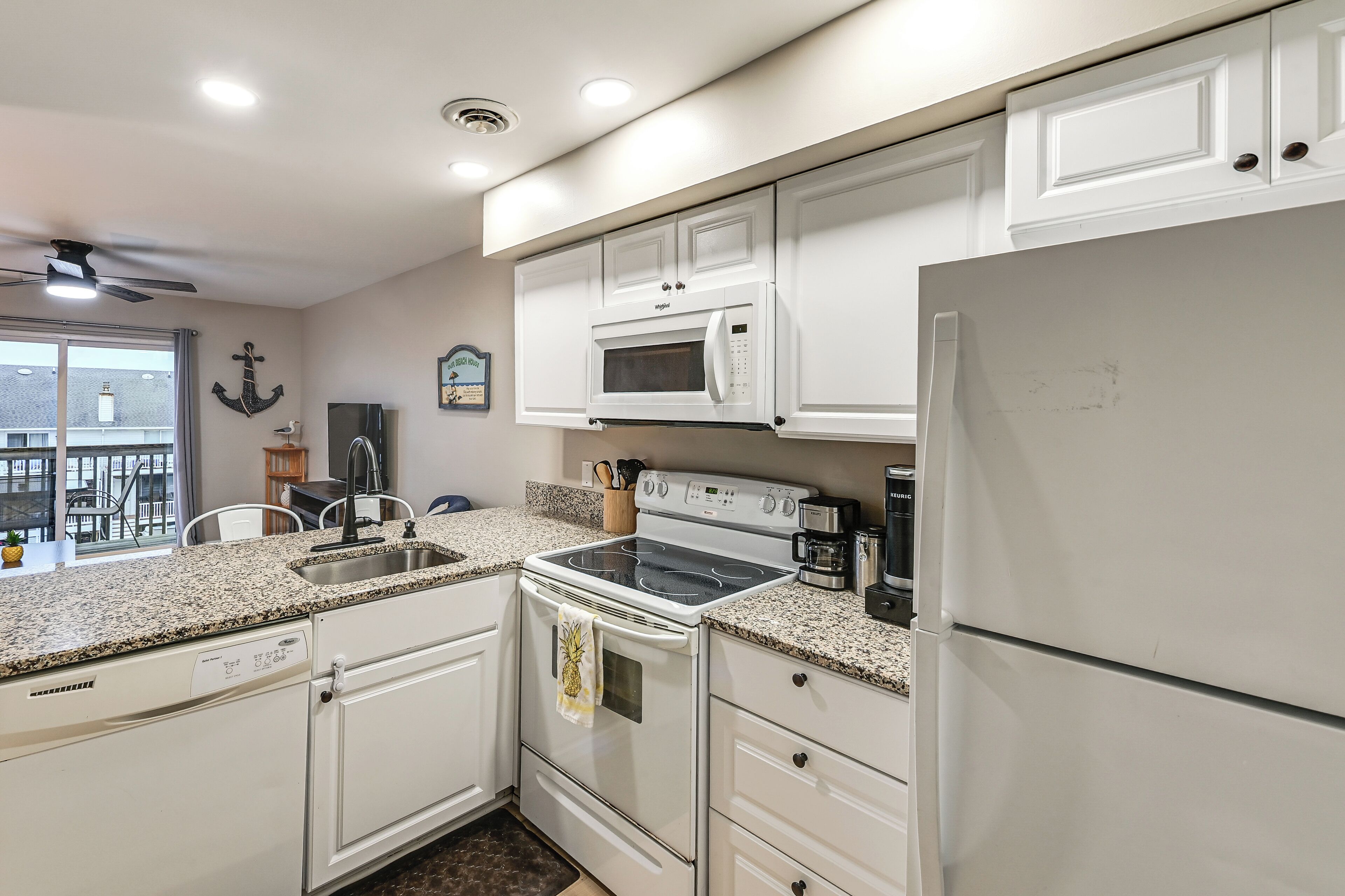 A kitchen with white cabinets, a microwave, an oven, a refrigerator, and a dishwasher.