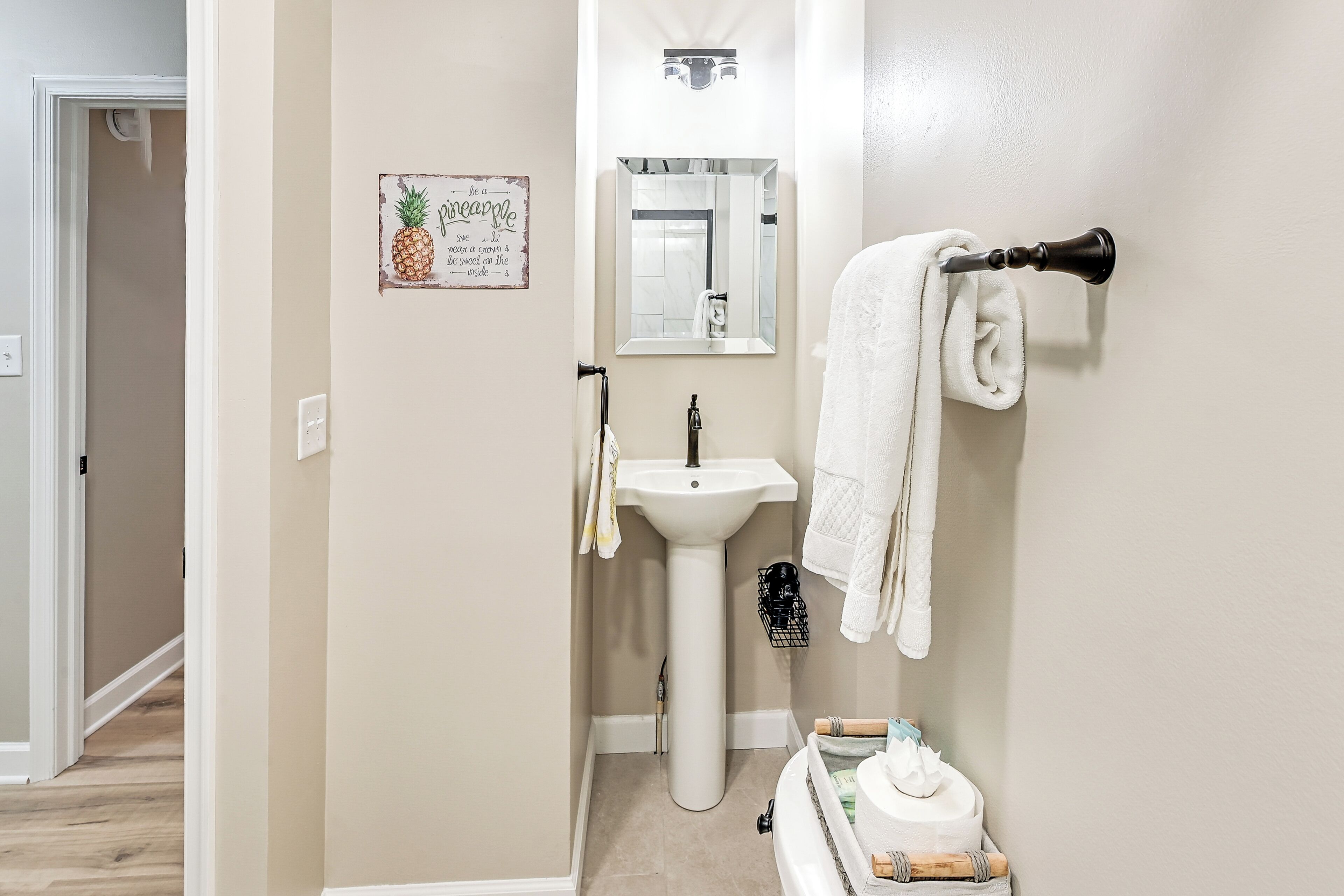 Une salle de bain avec un lavabo blanc, un miroir et un porte-serviettes.