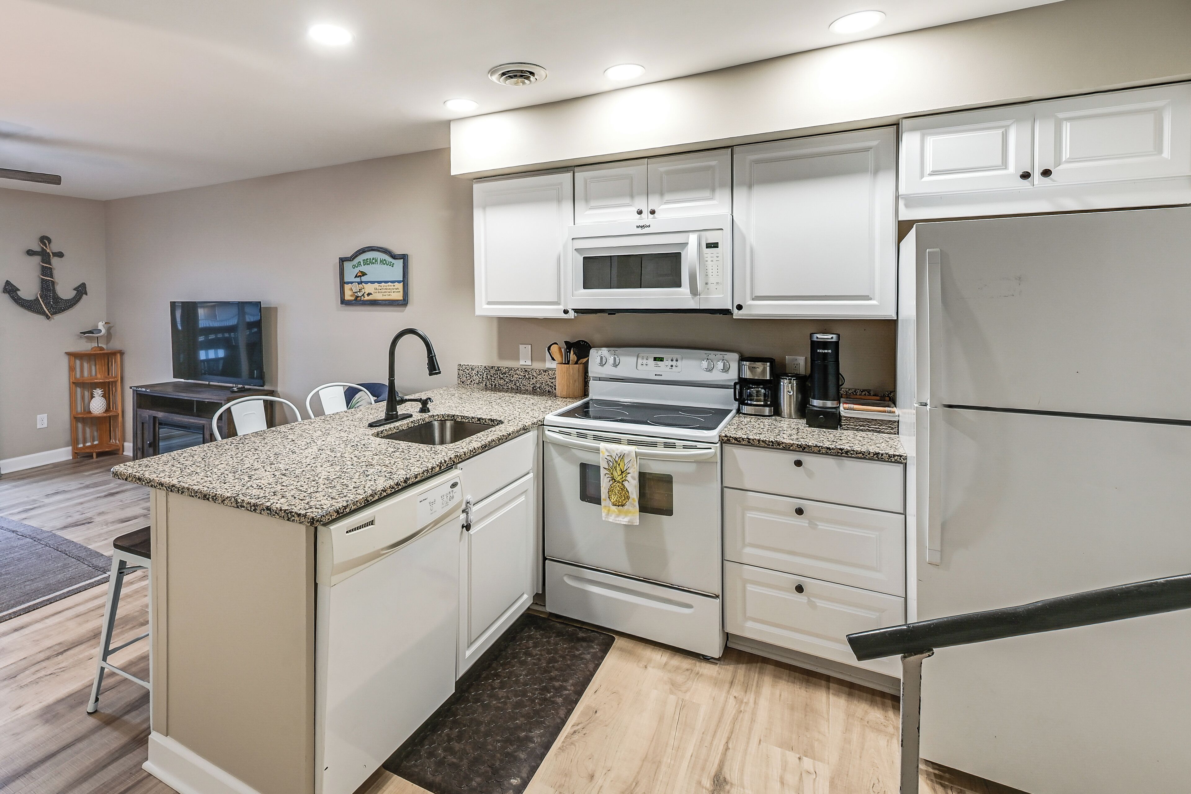 A modern kitchen with white cabinets, a granite countertop, a stainless steel range, and a built-in microwave.