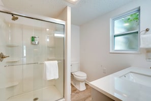 Ein modernes Badezimmer mit Duschkabine aus Glas, einer weißen Toilette und einem Waschbecken mit Spiegel.
