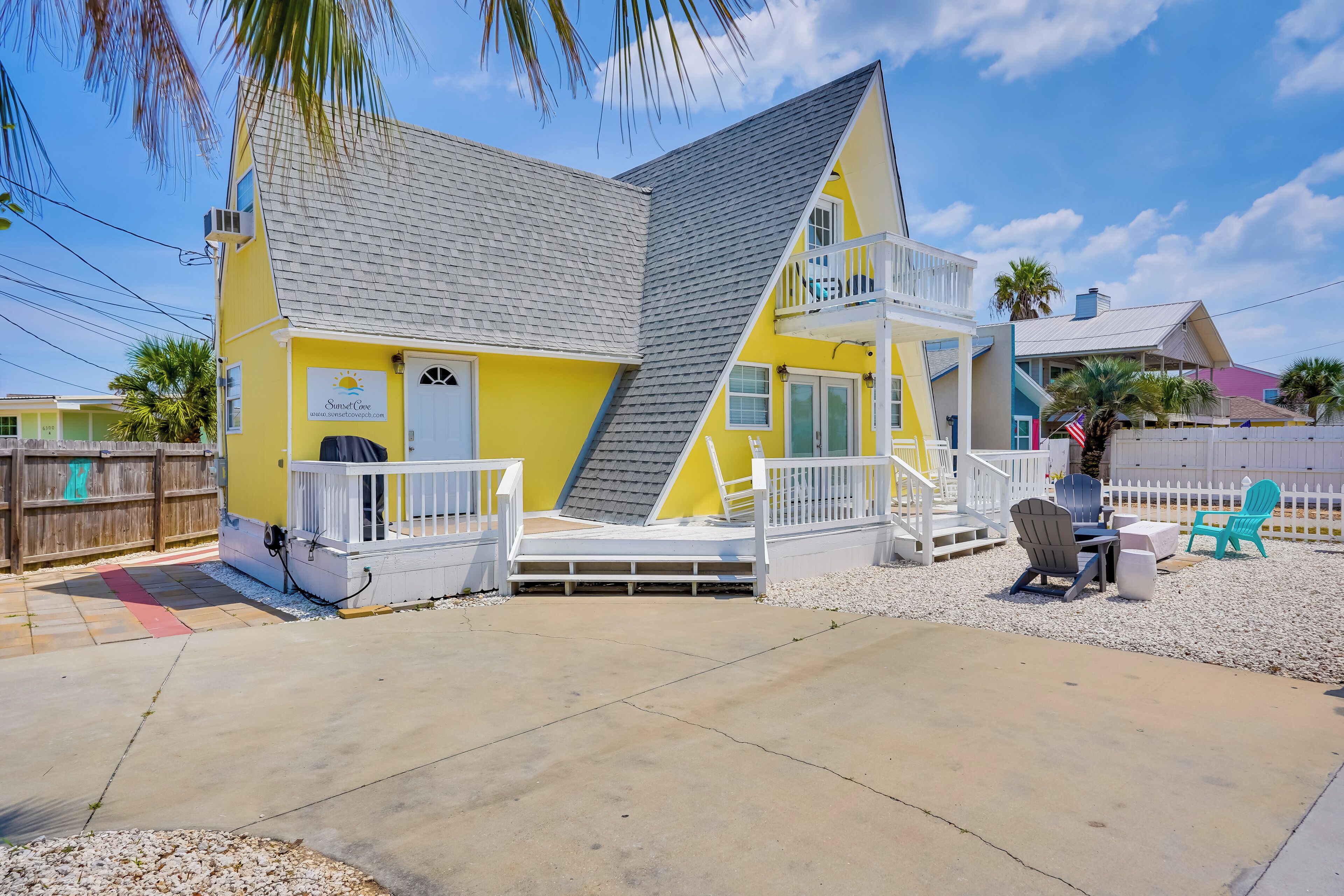 A yellow building with a white balcony, a small porch, and outdoor seating.
