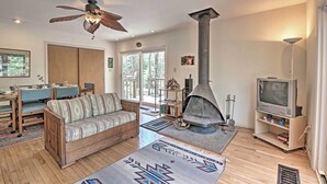 Una sala de estar con sofá, televisor, chimenea y ventilador de techo.