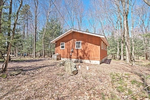 A wooden cabin surrounded by trees. - Creekside Arrowhead Lake House w/ Dock & Canoe! (Pocono Lake)