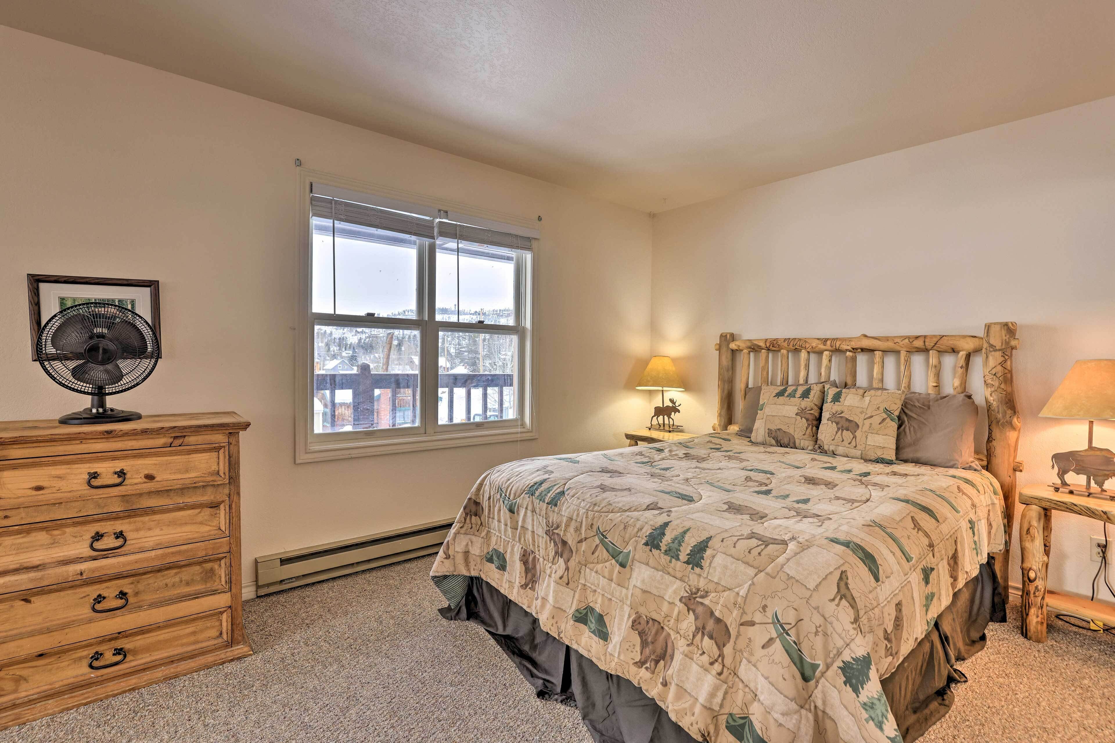 A bedroom with a bed, dresser, window, and a fan.