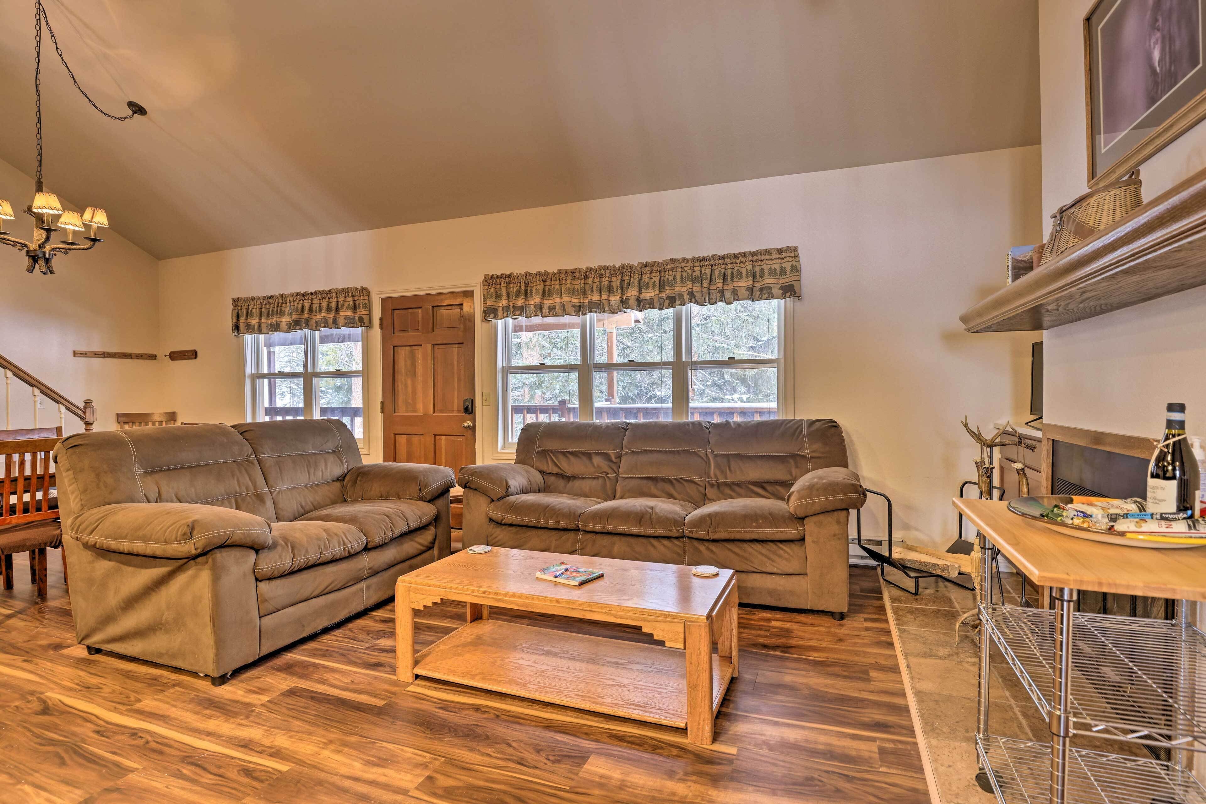 A living room with two brown leather sofas, a wooden coffee table, and a wooden dining table with a metal shelf.
