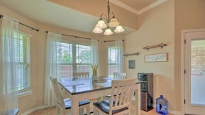 A dining area with a wooden table and white chairs, a water dispenser, and a large water jug.