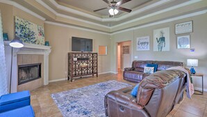 A living room with a fireplace, leather sofa, blue armchair, and a ceiling fan.