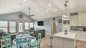 A spacious living area with a dining table, chairs, and a sofa. There is a kitchen with white cabinets and a bar area. - Ocean-view Deck, Walk to Shore: Crystal Beach Gem! (Port Bolivar)