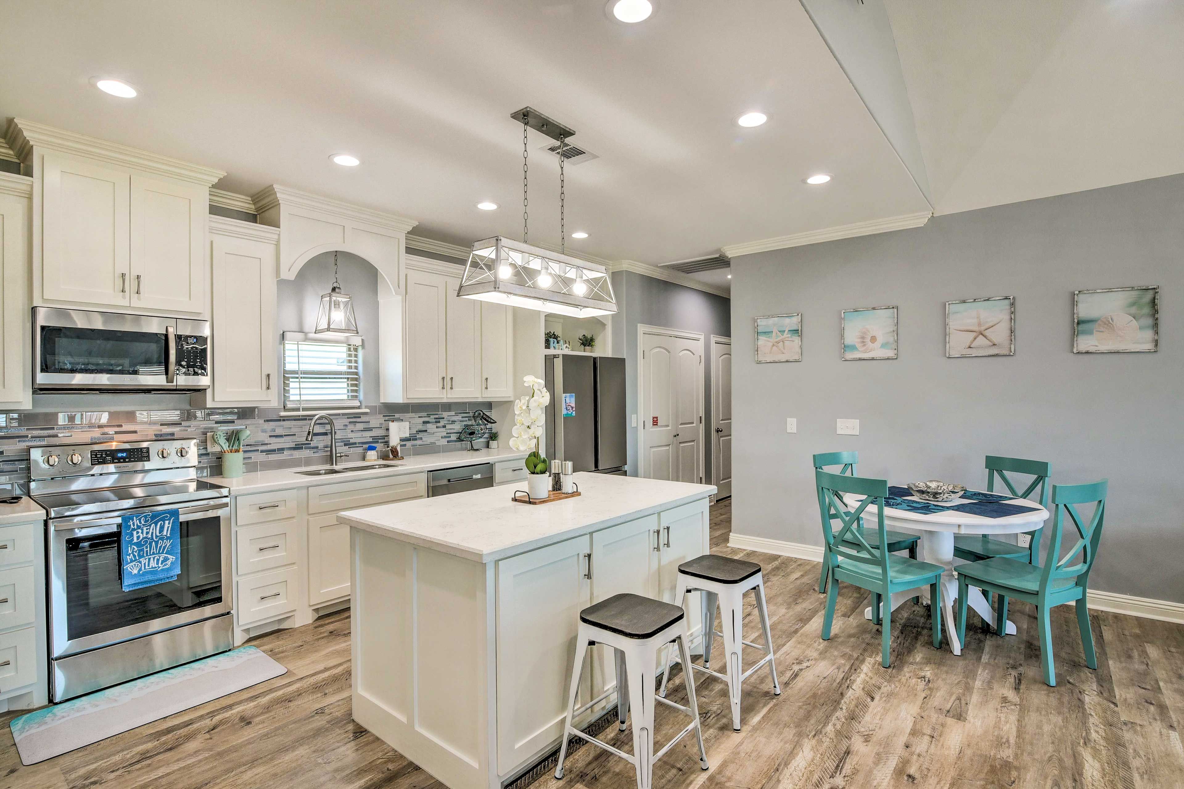 A modern kitchen with white cabinetry, stainless steel appliances, and a central island with bar stools.