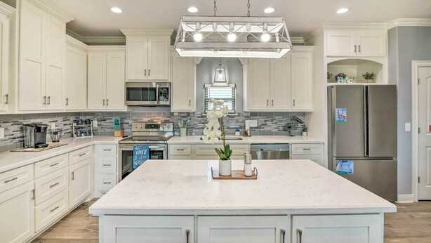 A modern kitchen with white cabinetry, a central island, stainless steel appliances, and a pendant light fixture. - Ocean-view Deck, Walk to Shore: Crystal Beach Gem! (Port Bolivar)
