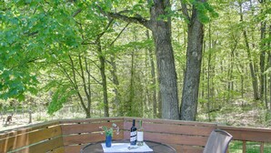 A wooden bench and table set in a forested area with a view of trees and a picnic table.