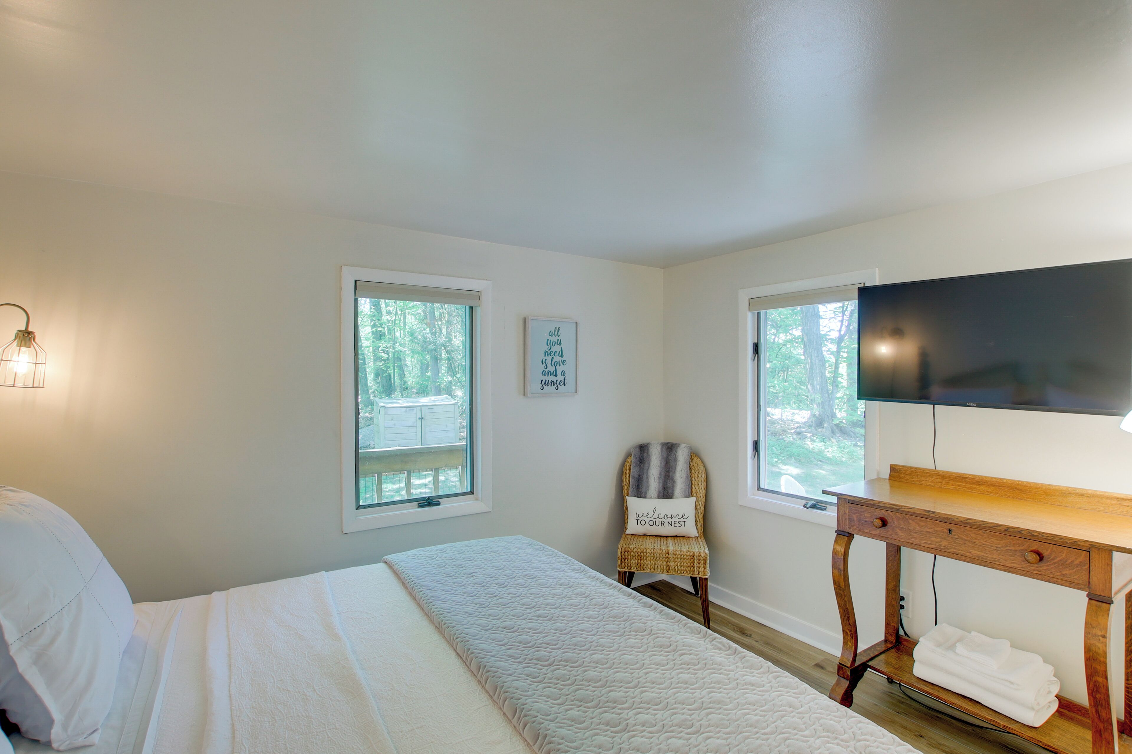 A bedroom with a bed, a wooden nightstand, a chair, and a TV.