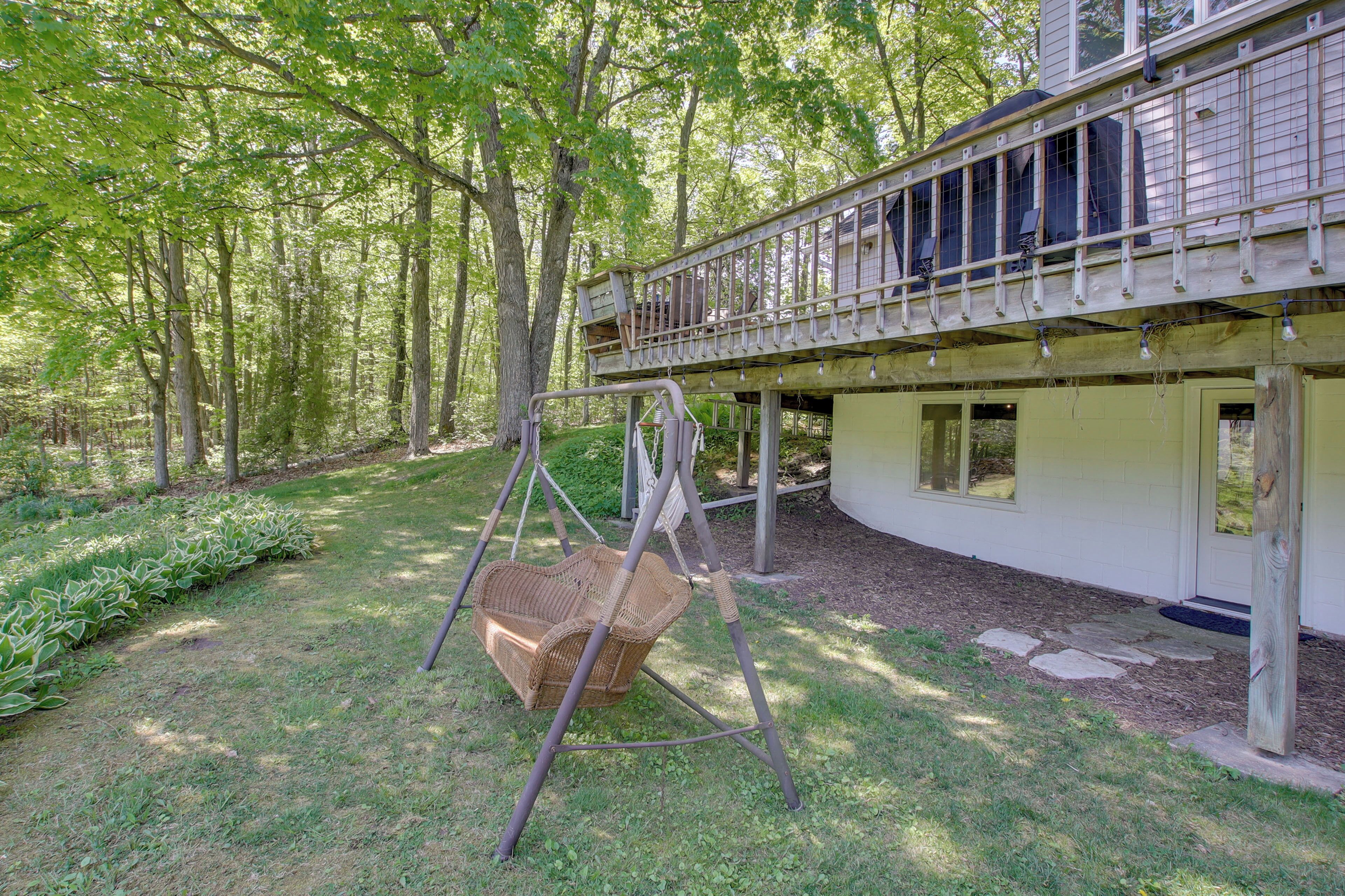 Une maison avec une véranda, une chaise suspendue et une terrasse en bois.