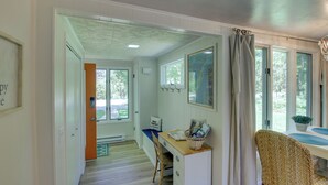 A room with a desk, chair, and a window with curtains. There is a door leading to another room.