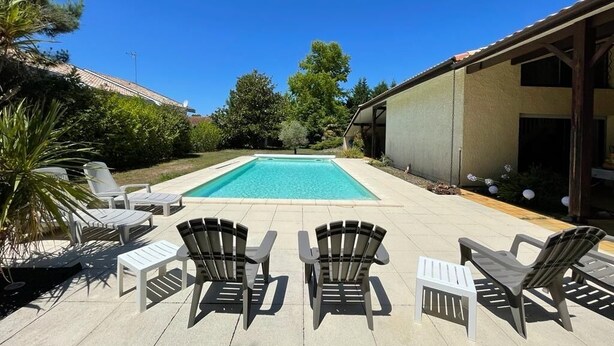 A swimming pool with lounge chairs and a covered patio area. - Vacation villa / Swimming pool, lake, forest (biscarrosse)