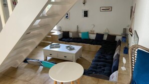 A modern living room with a large sectional sofa, a white coffee table, and a staircase leading to an upper level. - Vacation villa / Swimming pool, lake, forest (biscarrosse)