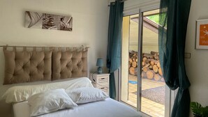 A bedroom with a large bed, a bedside table with a lamp, a window with curtains, and a framed picture on the wall. - Vacation villa / Swimming pool, lake, forest (biscarrosse)