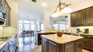 A spacious kitchen with dark cabinetry, a large island, and a dining area with a table and chairs.
