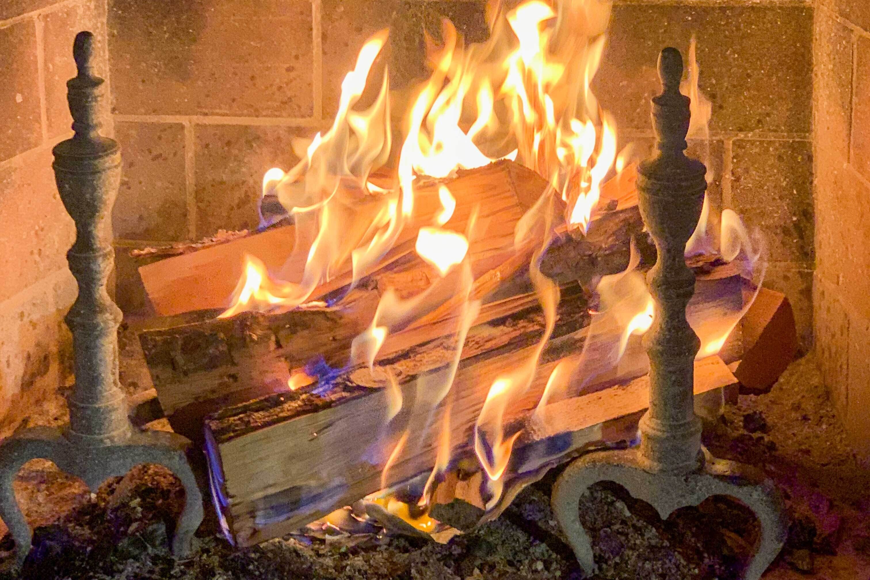 Ein Kamin mit brennenden Holzscheiten und dekorativen Metallständern.