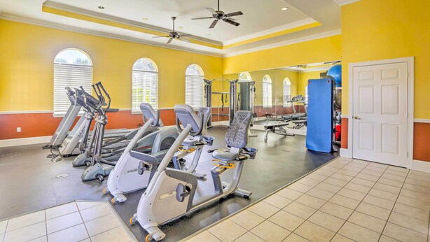 A gym with treadmills, ellipticals, and a mirrored wall.