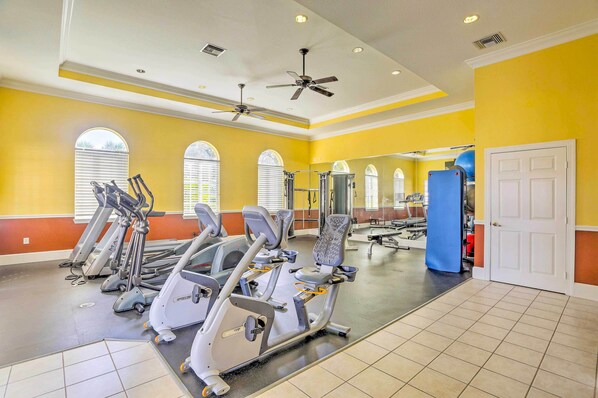 A gym with treadmills, ellipticals, and a mirrored wall.