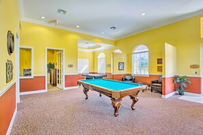 A pool table in a room with yellow walls and a carpeted floor.