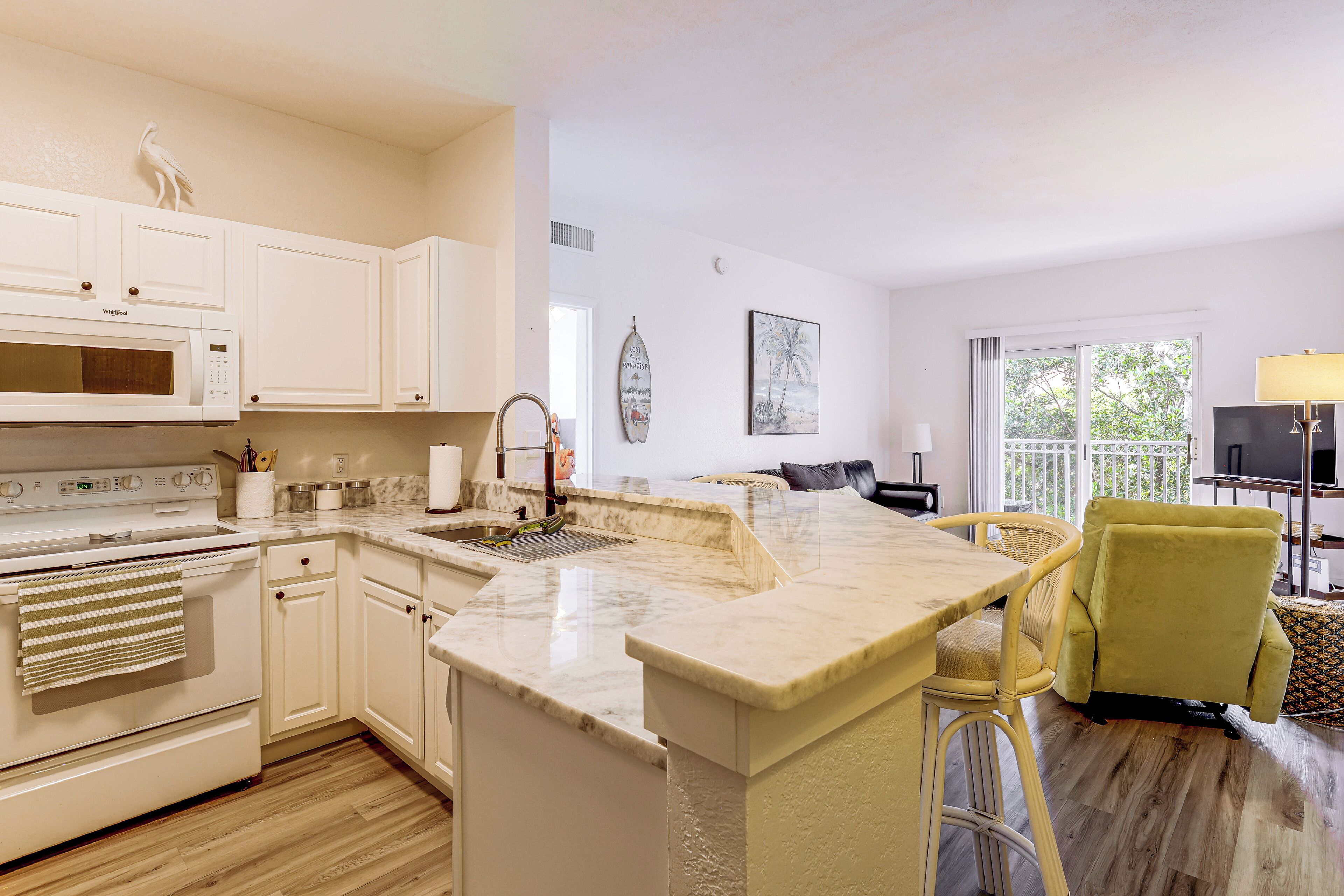 A kitchen with white cabinetry, a built-in microwave, and a large island with a sink.